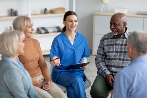 Nurse sitting and talking to a group of seniors.