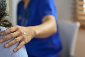 Woman supporting another person with hand on shoulder