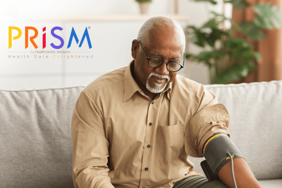 Older man sitting on couch taking blood pressure