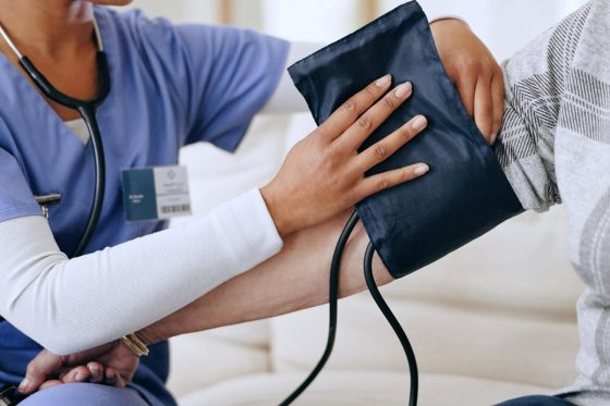 Healthcare worker applying a blood pressure cuff to a female senior patient