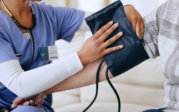 Healthcare worker applying a blood pressure cuff to a female senior patient