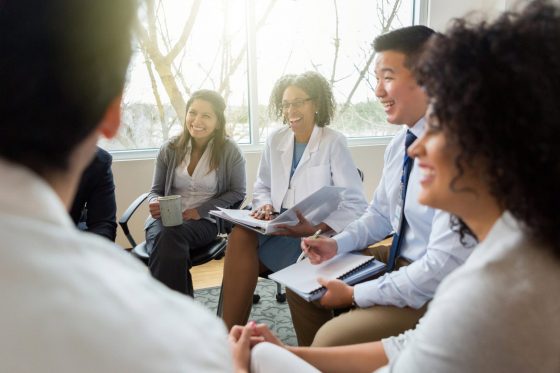 Team of healthcare professionals at a meeting smiling.