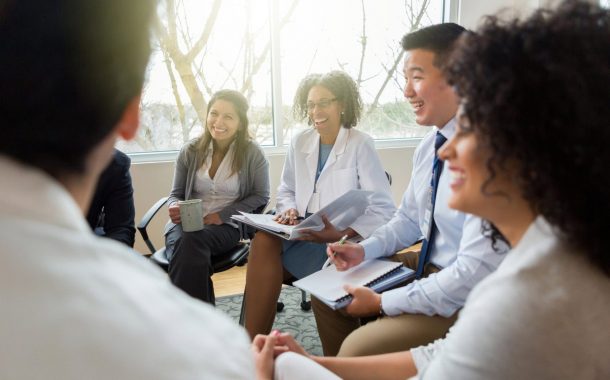 Team of healthcare professionals at a meeting smiling.